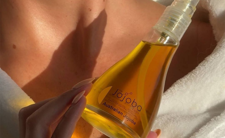 closeup of woman hold bottle of the jojoba company oil